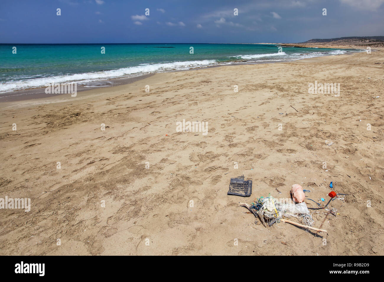 Schönen wilden natürlichen Strand, keine Menschen, ruhig azurblauen Meer im Hintergrund, Haufen Müll im Vordergrund. Meeresverschmutzung Konzept. Stockfoto