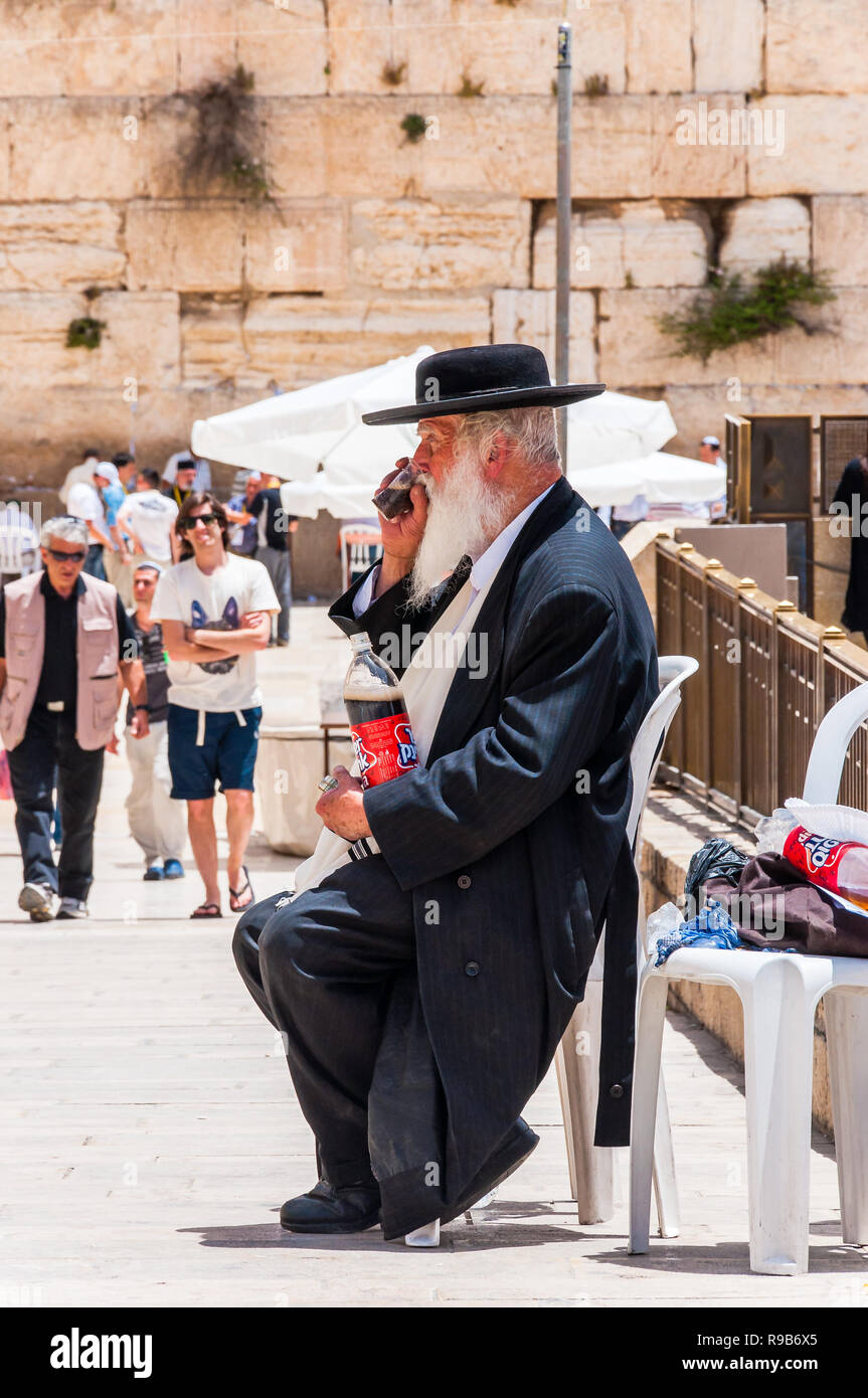Jerusalem, Israel - 25. Mai 2012: jüdisch-orthodoxen im schwarzen Anzug und Hut sitzen und trinken in der Nähe der Einfahrt Gasse an der westlichen Mauer. Menschen, Loca Stockfoto