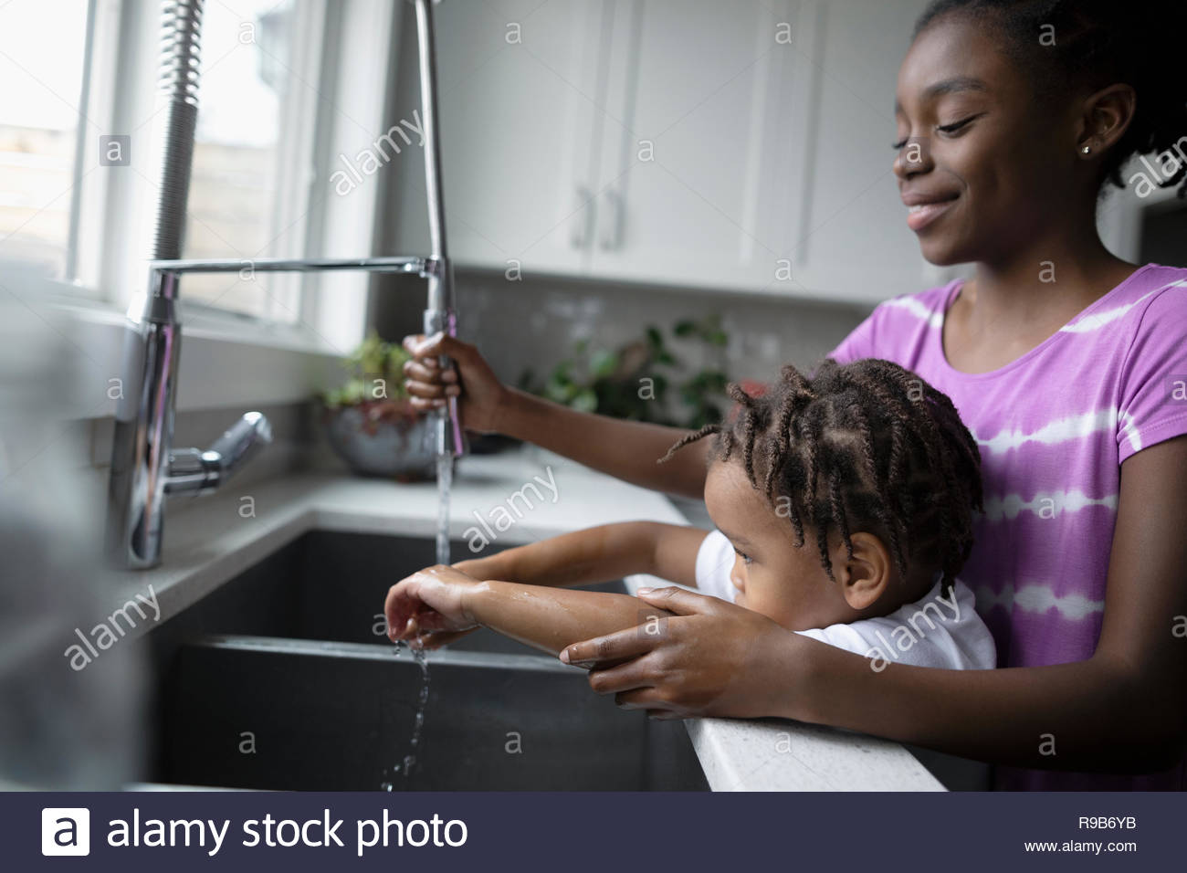 Schwester helfen toddler Bruder Waschen der Hände am Waschbecken Stockfoto