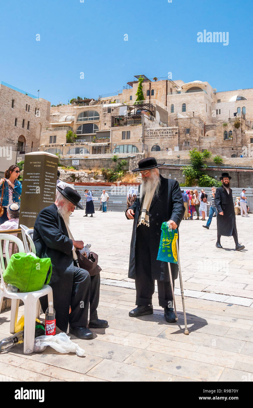 Jerusalem, Israel - 25. Mai 2012: Zwei alte Jüdische orthodoxe Männer in schwarzen Anzügen und Hüte trinken Limonade und die Unterhaltung in der Nähe der Einfahrt Gasse an den Wes Stockfoto