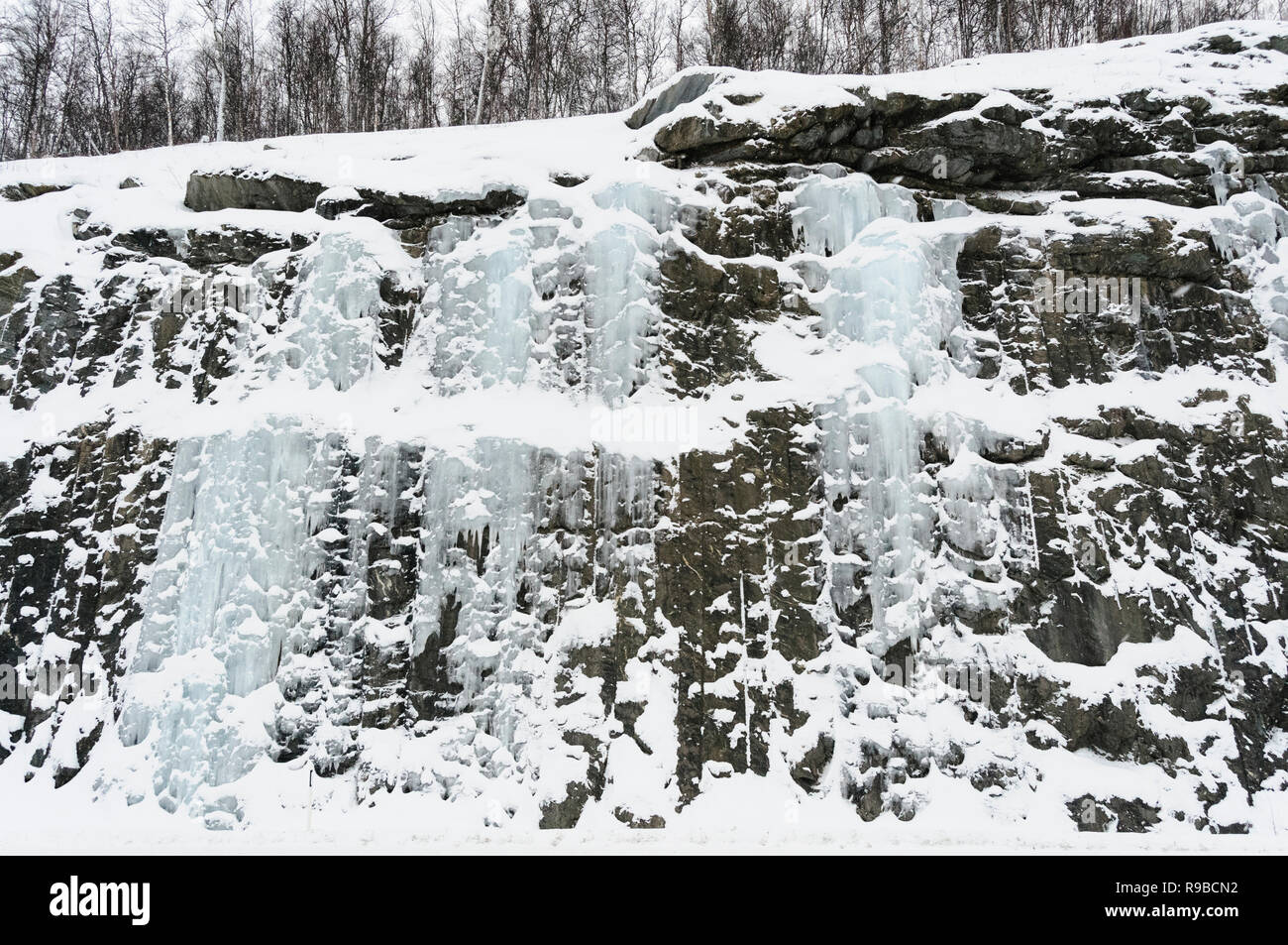 Gefrorenen Wasserfall mit Eiszapfen, Felsen und Schnee in der Nähe von Tromsö in Das arktische Norwegen Stockfoto