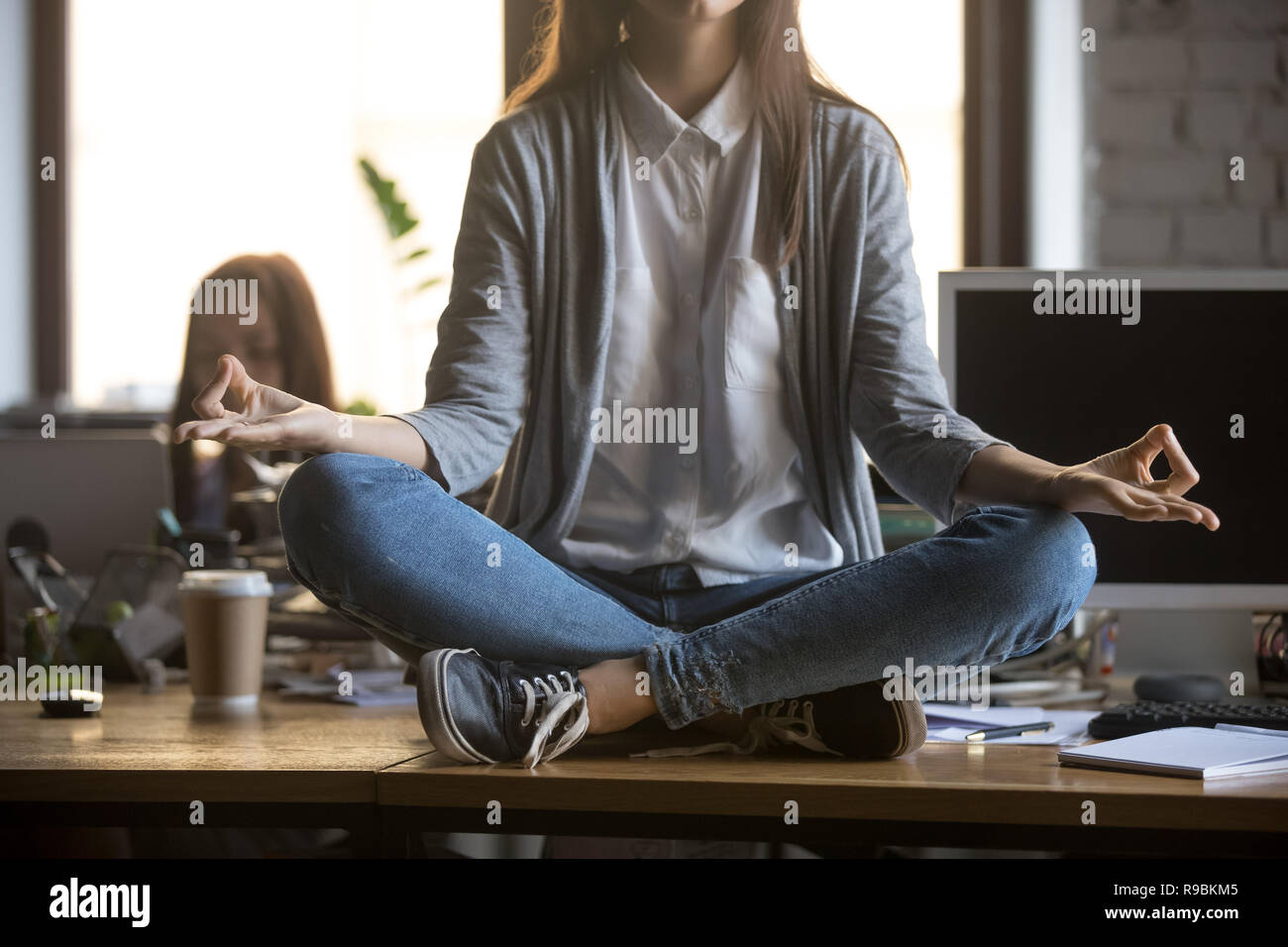 Frau sitzt am Schreibtisch im Lotussitz Yoga Übung Stockfoto
