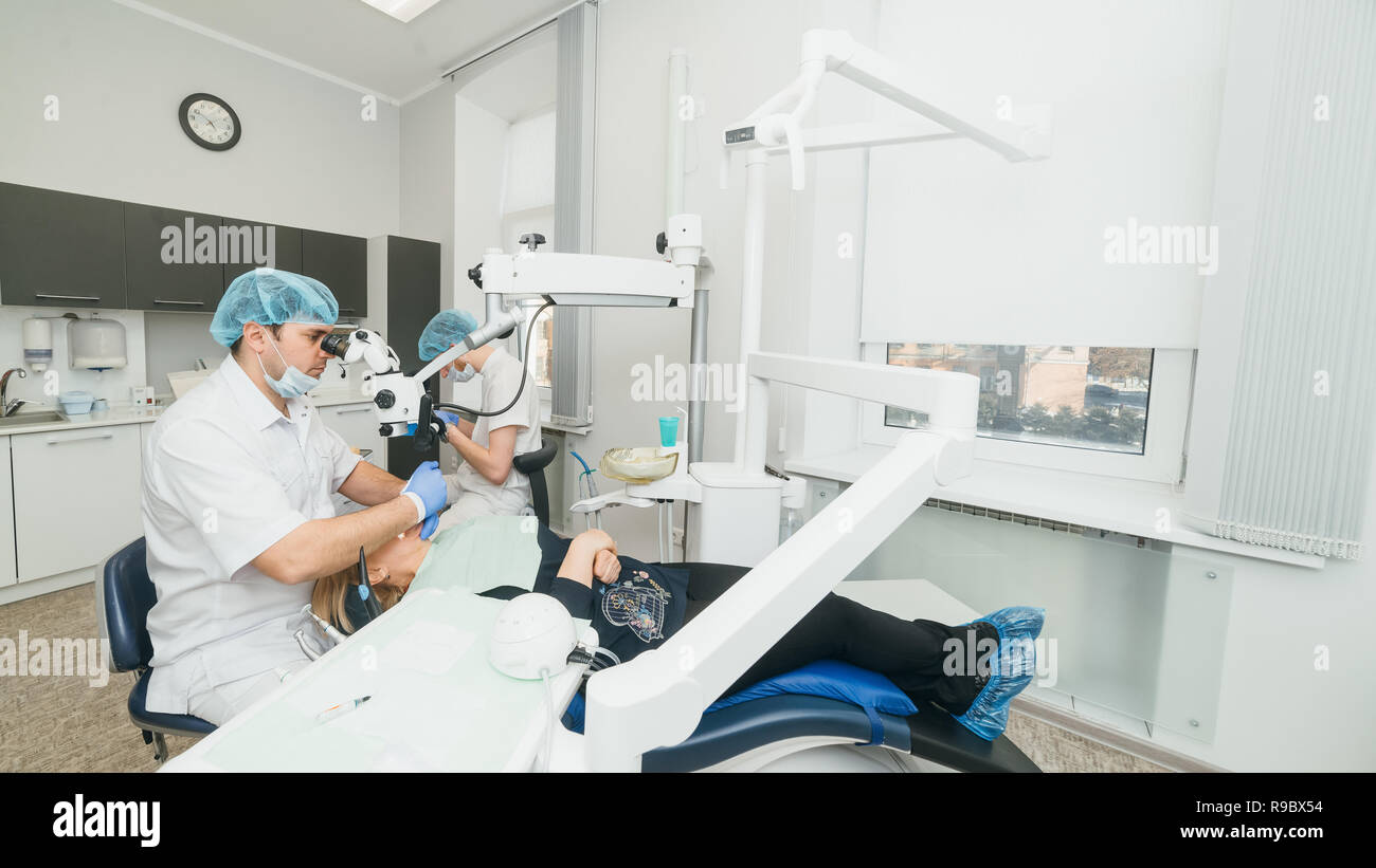 Arzt Mikroskop. Zahnarzt ist die Behandlung von Patienten in der modernen zahnmedizinischen Büro. Die Bedienung erfolgt mittels Fangdamms durchgeführt. Client wird eingefügt und restauriert, Zähne, Zahnersatz. Stockfoto