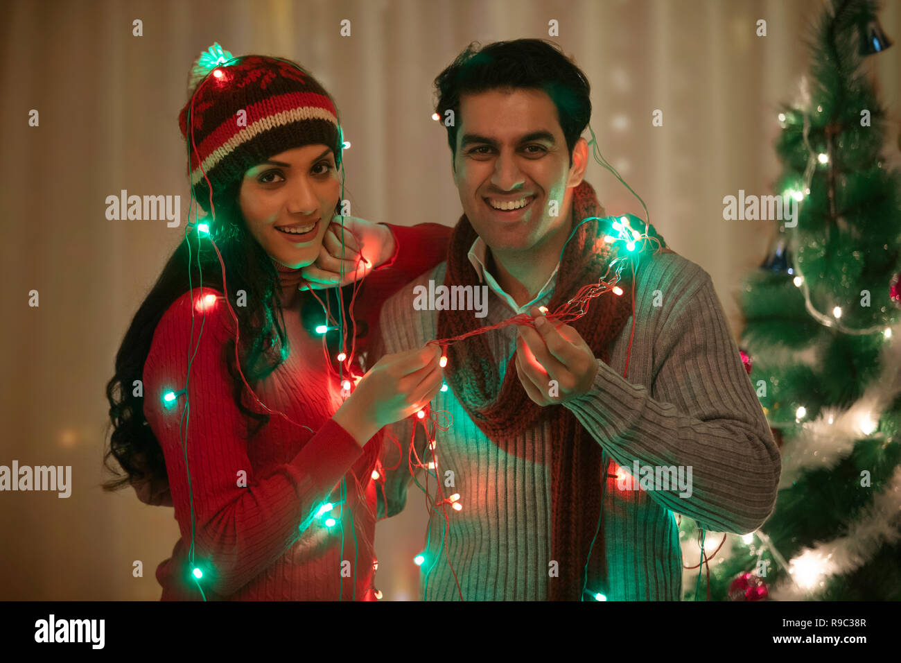 Junges Paar verpackt fairy Licht an Weihnachten feiern Stockfoto