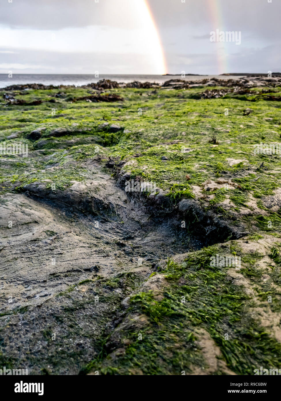 Regenbogen über der berühmten Fußabdrücke von Dinosauriern zu einem corran Strand von staffin auf die Isle of Skye - Schottland Stockfoto