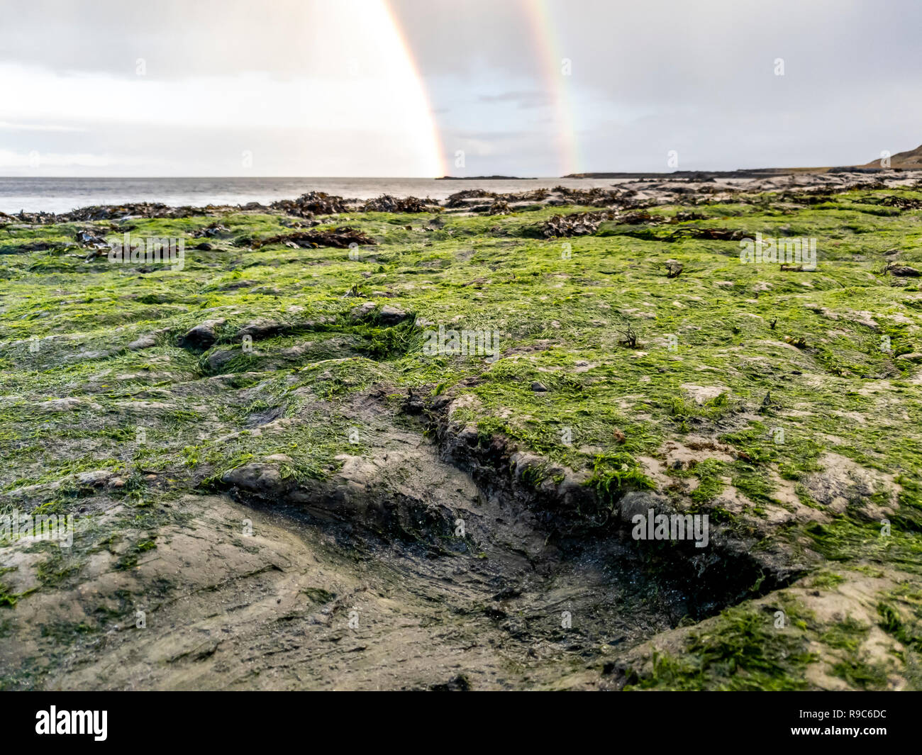 Regenbogen über der berühmten Fußabdrücke von Dinosauriern zu einem corran Strand von staffin auf die Isle of Skye - Schottland Stockfoto