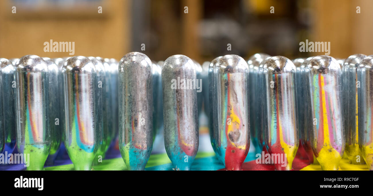 Leere Lachgas cannisters reflektierende psychedelischen Farben: Metall Zylinder mit Lachgas, für Schlagsahne eingesetzt, aber auch als rechtliche Stockfoto