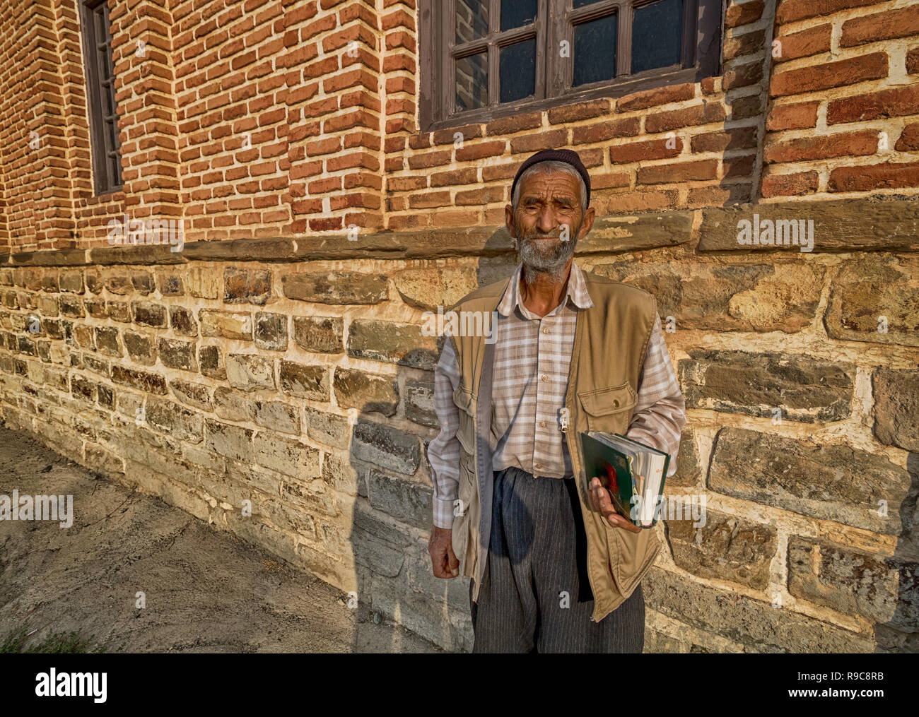 Ein alter Mann auf dem Bürgersteig mit einem Buch an Kamera suchen Stockfoto