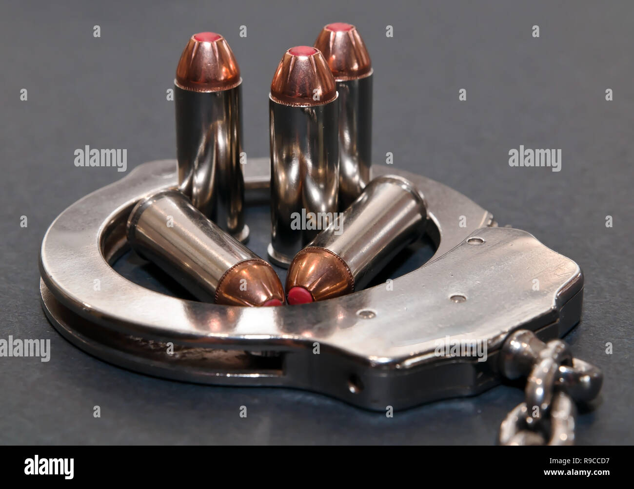 Fünf 44 spl rote Spitze Kugeln innerhalb einer Metall Handschellen auf grauem Hintergrund Stockfoto