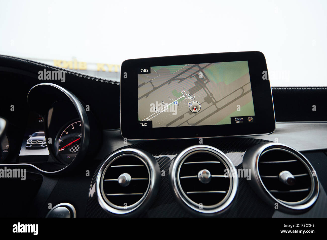 Blick vom in einem Auto auf einen Teil des Dashboards mit einer Navigationseinheit und unscharfen Straße vor ein Auto Stockfoto