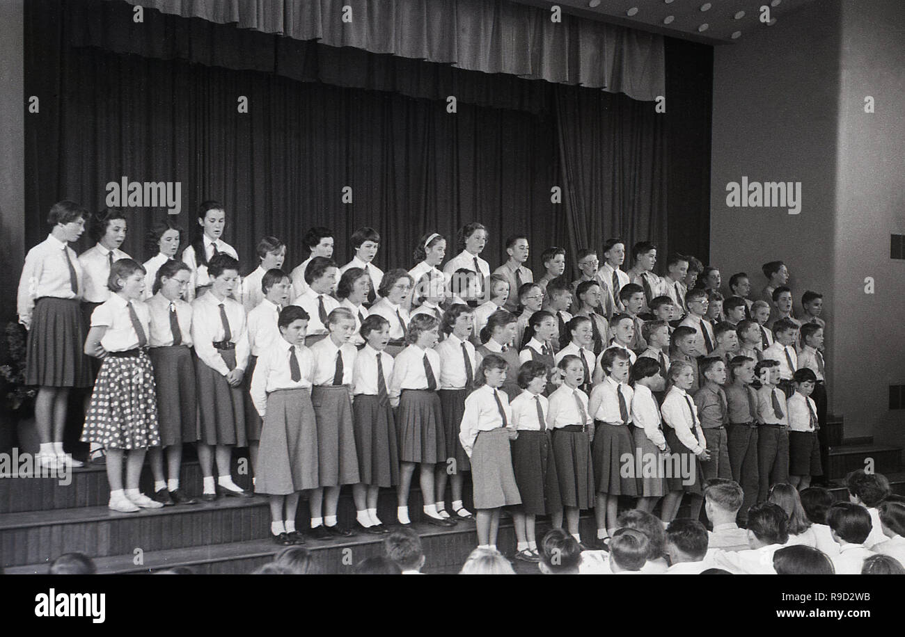 1950, historische, eine Gruppe von uniformierten Schule Kinder singen auf der Bühne in einer Schule Hall, England, Großbritannien Stockfoto