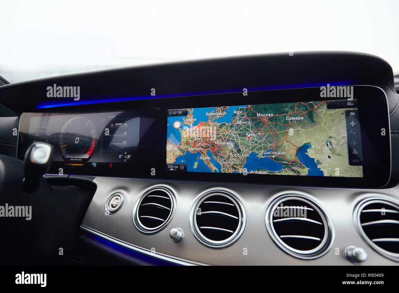 Blick vom in einem Auto auf einen Teil des Dashboards mit einer Navigationseinheit und unscharfen Straße vor ein Auto Stockfoto