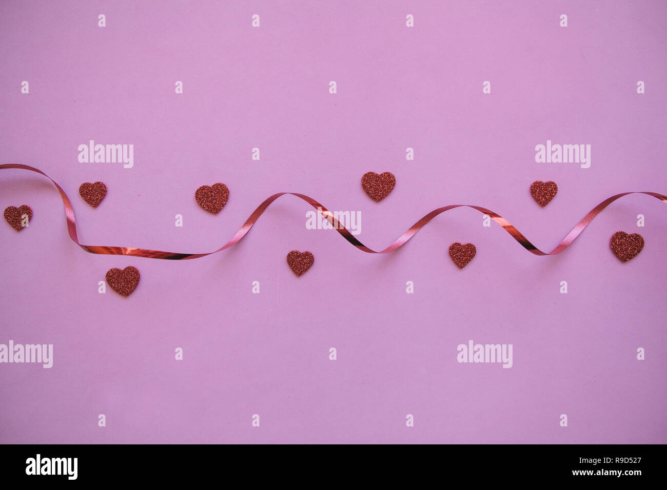 Red Ribbon und viele kleine Herzen. Valentine's Day Feier Konzept im minimalistischen Stil. Urlaub Elemente. Stockfoto