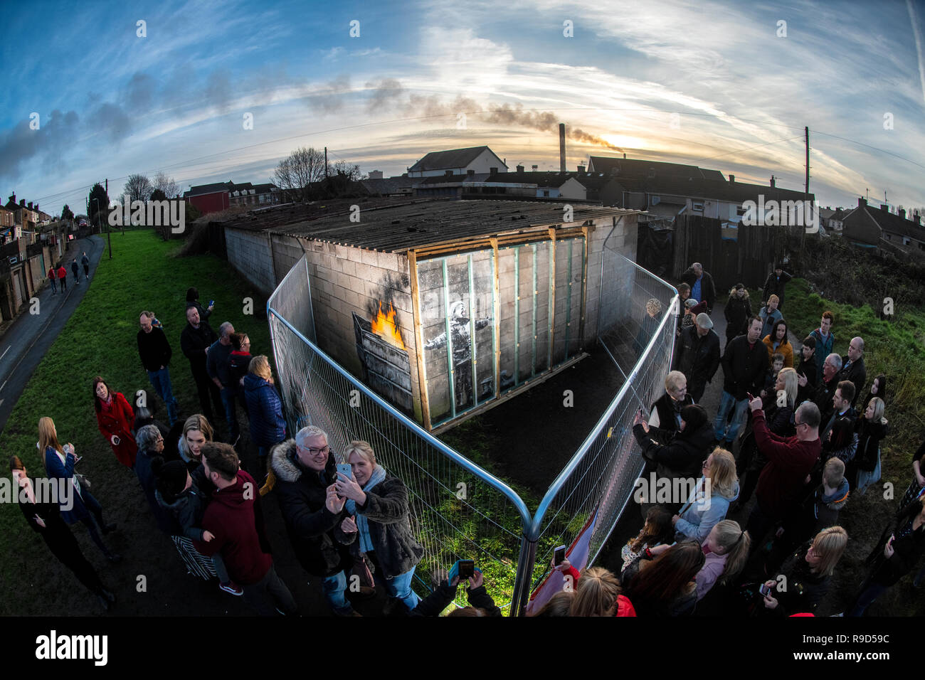 Die Menschen sammeln sich um Zäune errichtet die neuesten Kunstwerke von Banksy auf eine Garage an der Wand in der Taibach Bereich von Port Talbot in South Wales zu schützen. Stockfoto