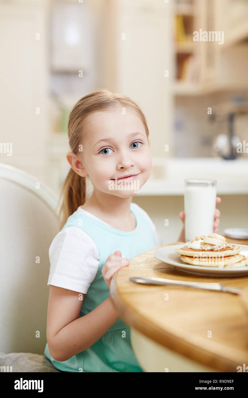 Süße Mädchen trinken Milch mit Pfannkuchen Stockfoto