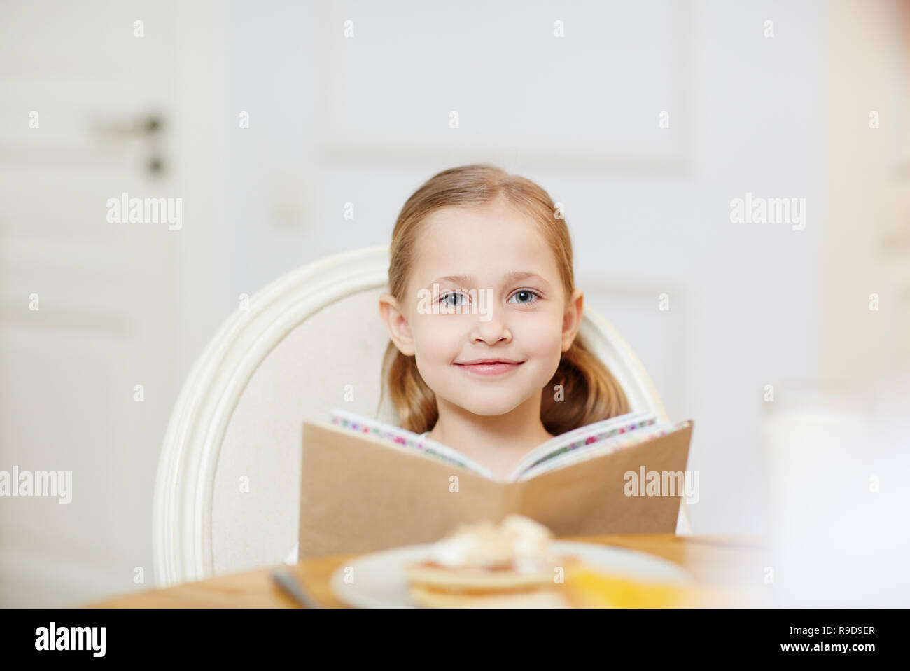 Lächelnde Mädchen lesen Buch in der Küche Stockfoto