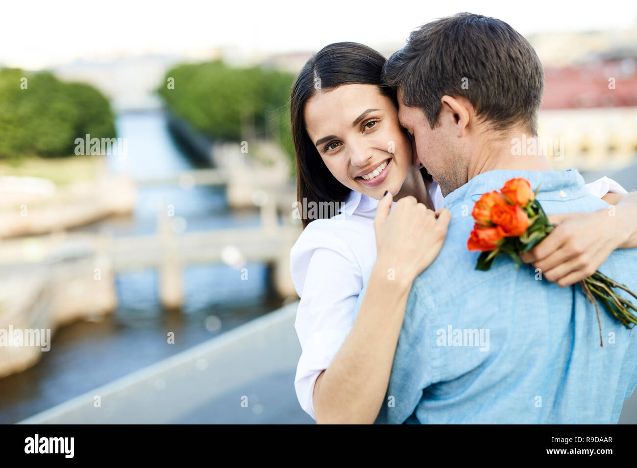 Glückliche Freundin mit Blumenstrauß ihr Mann kuscheln Stockfoto