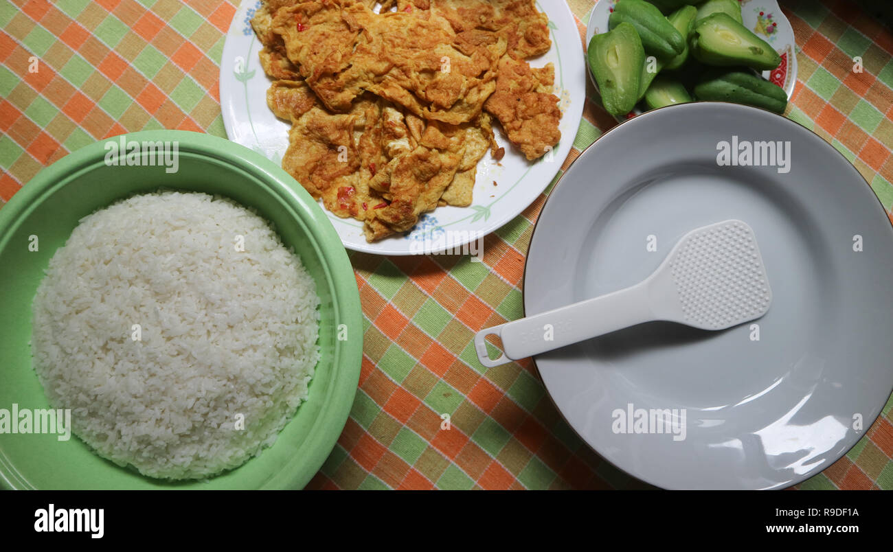 Weißer Reis, Spiegelei, grüne Kürbisse auf dem Tisch Stockfoto