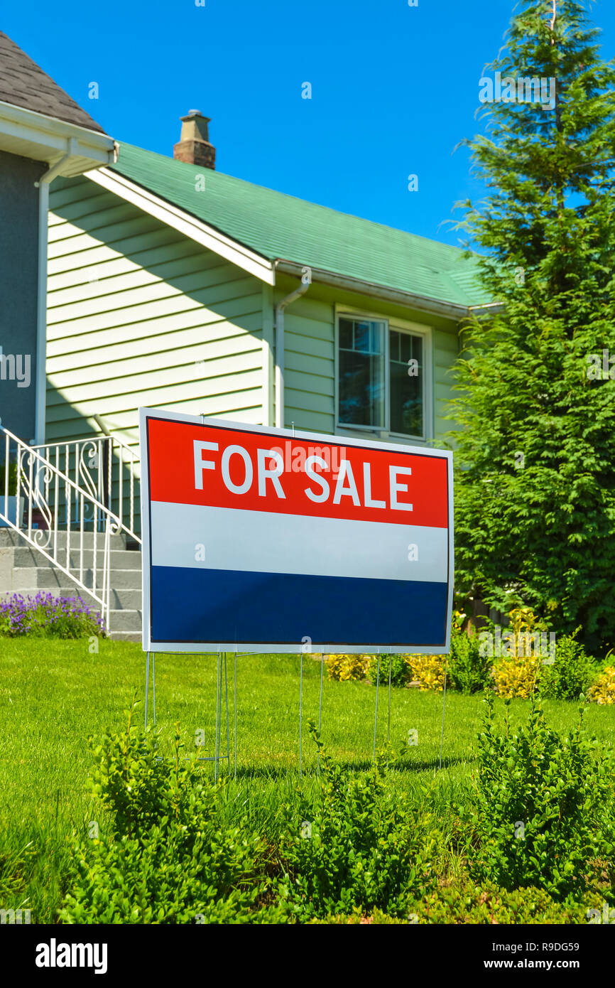 Immobilien Schild "Zum Verkauf" im Vorgarten eines Hauses Stockfoto