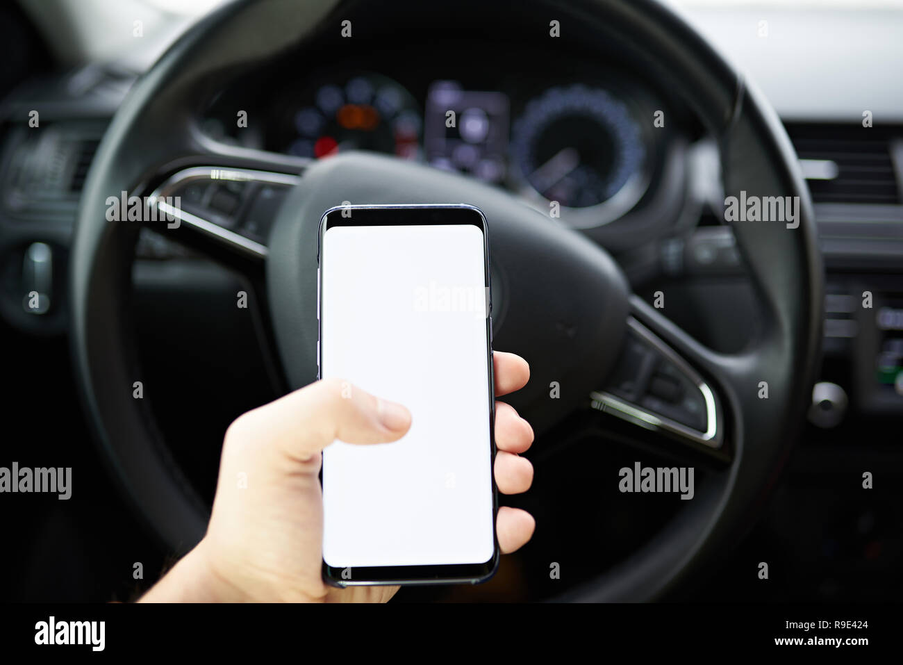 Sie ihr Smartphone während der Fahrt. Handy in der Hand mockup auf blur Auto Hintergrund Stockfoto