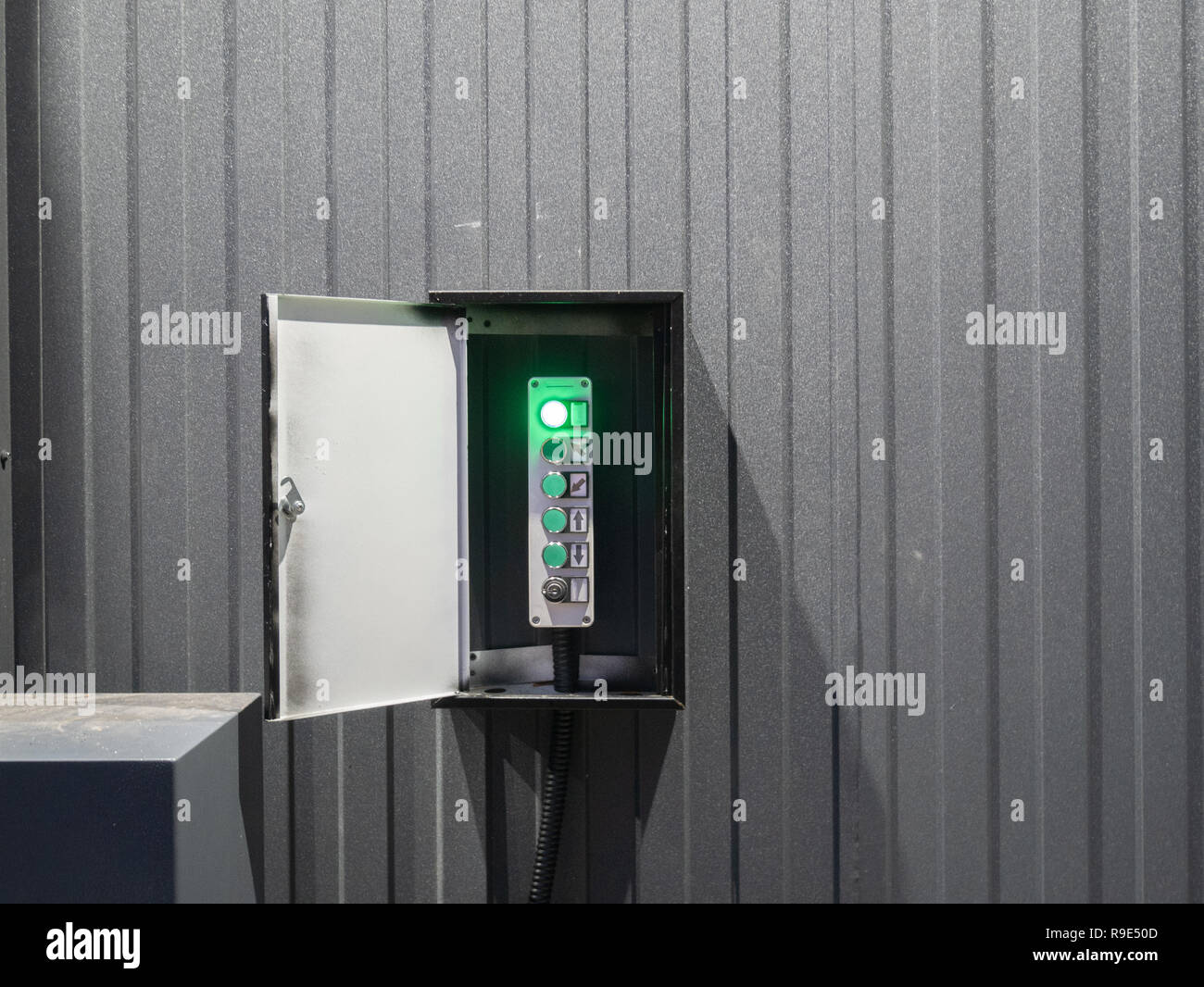 Geöffnete Verpackung mit industriellen lift Lift control board auf Lager oder Werk, viele Tasten mit graue Wand auf Hintergrund. Grüne Lampe leuchtet als in Stockfoto