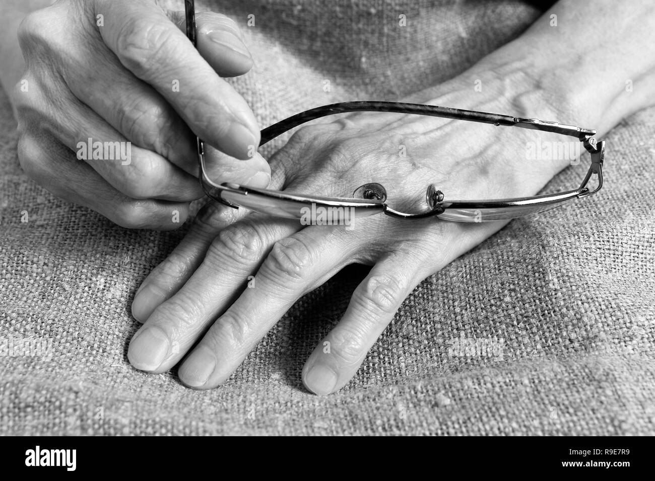 Gläser in die Hände einer alten Frau. Teil des Körpers. Stockfoto