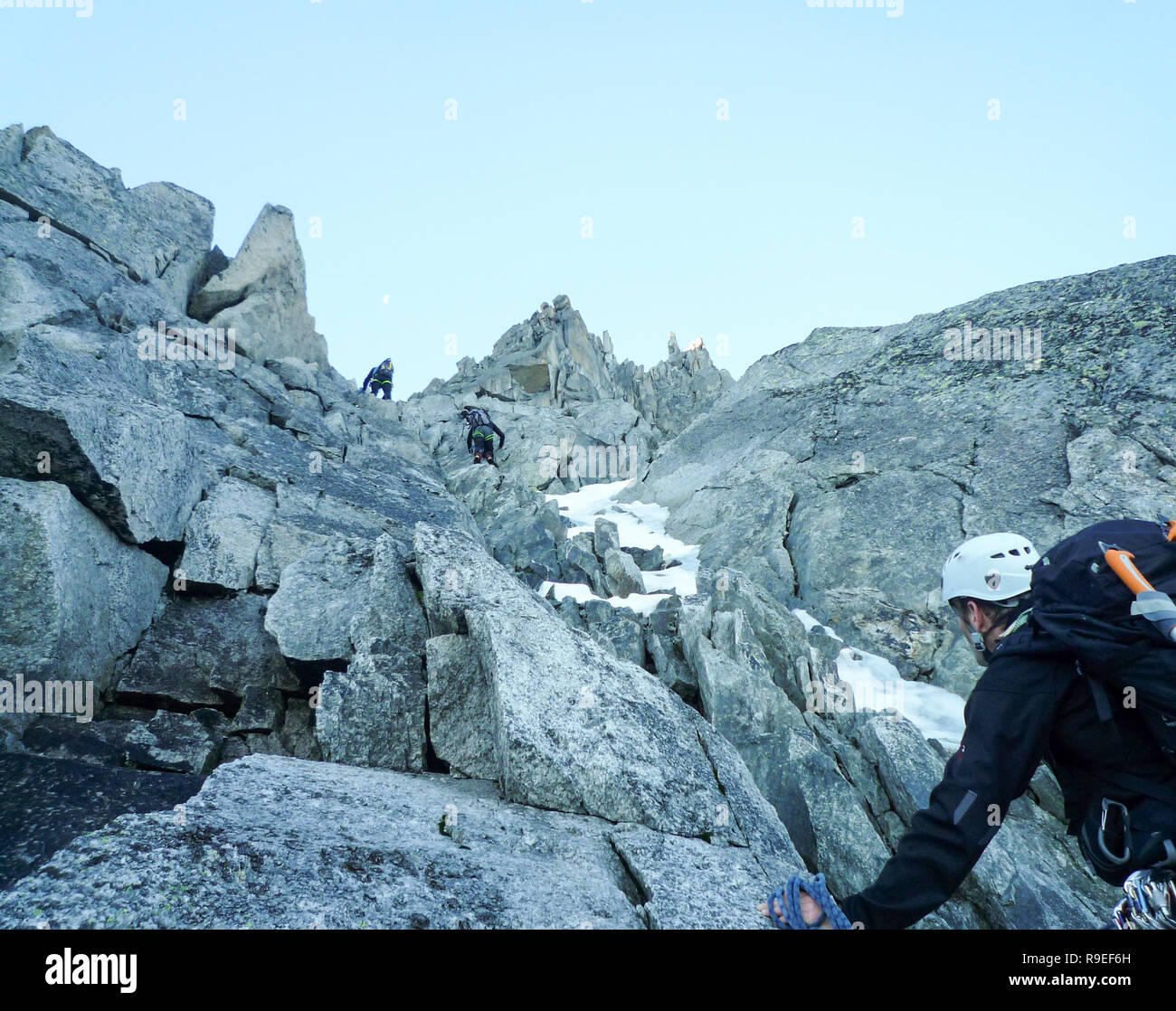 Bergführer suchen, um sich auf einem felsigen Aufstieg in den französischen Alpen mit Seil Teams vor ihm Stockfoto