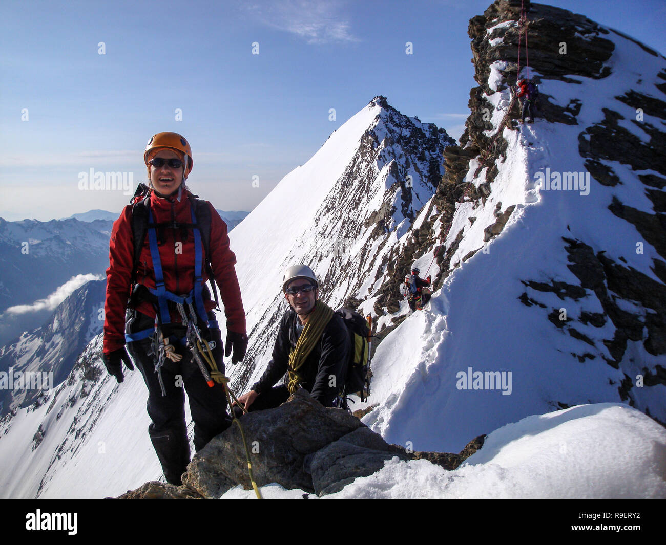 Frau und Mann Bergsteiger auf dem Weg zu einem hohen Berg entlang einer schmalen felsigen Grat Stockfoto