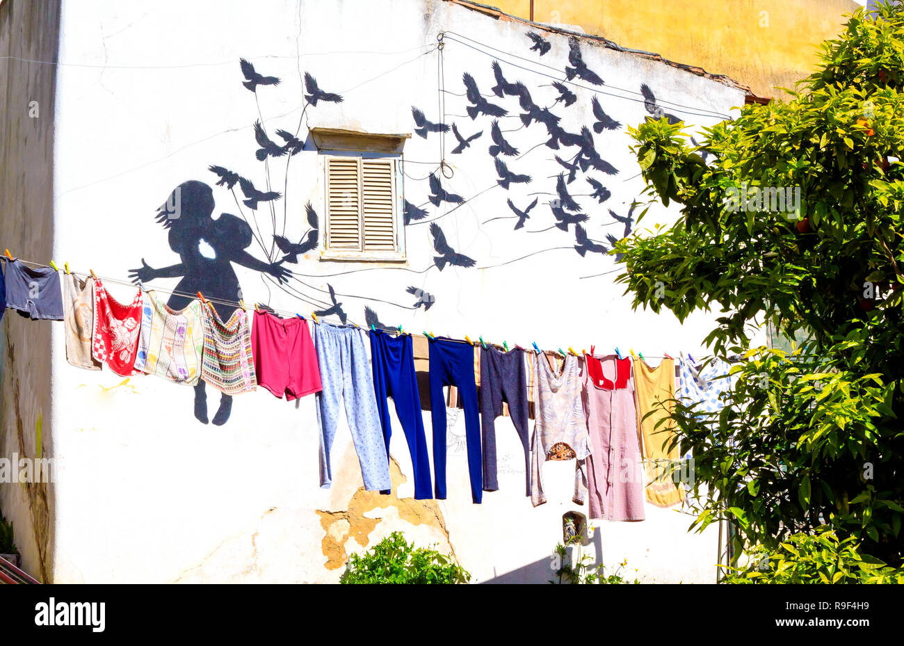 Ehrfurcht-Graffiti-Gemälde, das ein Mädchen und einen Vogelschwarm an der Gebäudewand in der versteckten Ecke von Alfama in Lissabon, Portugal, darstellt. Stockfoto