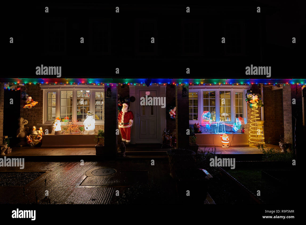 Weihnachtsbeleuchtung und Dekoration an der Vorderseite eines Hauses auf einem nassen Winter Abend Stockfoto