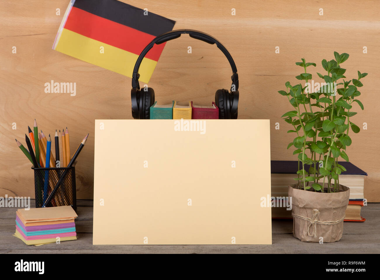 Das Konzept des Lernens der deutschen Sprache - leeres Papier, Flagge der Deutschland, Bücher, Kopfhörer, Bleistifte auf hölzernen Hintergrund Stockfoto