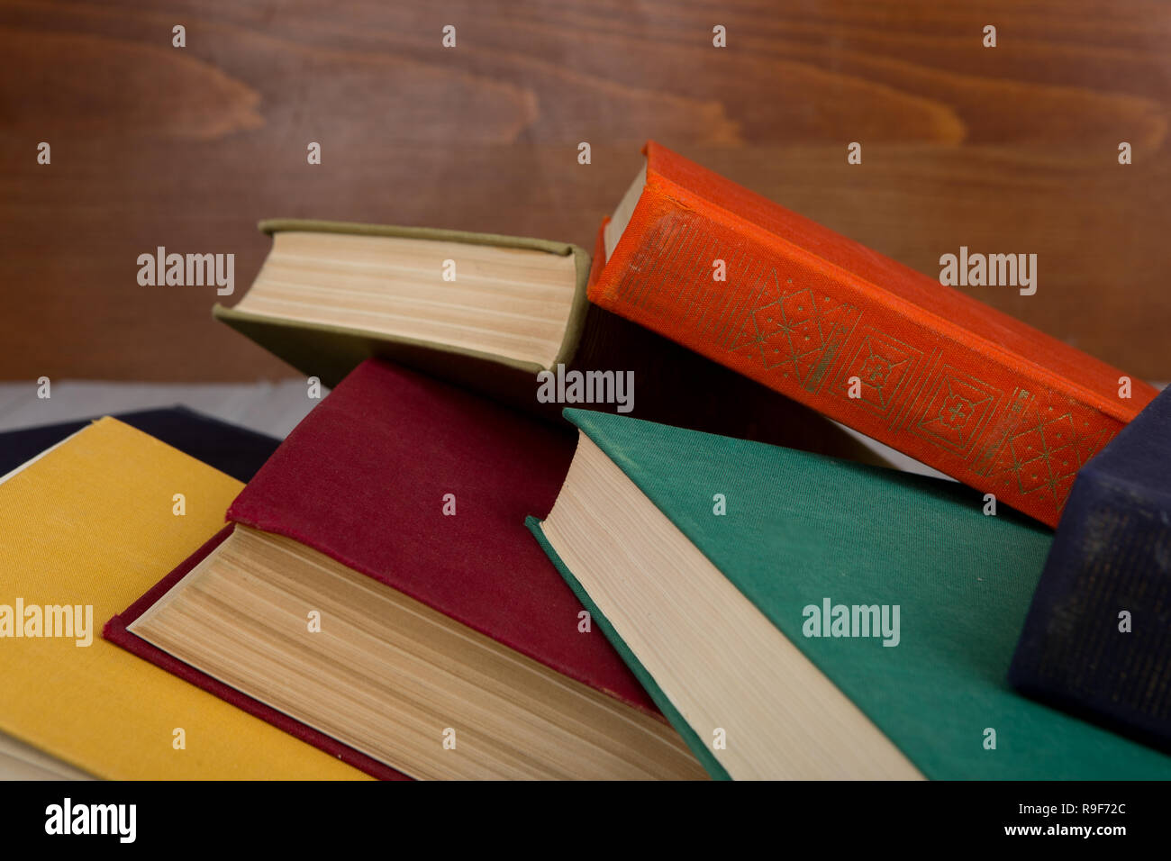 Zurück zu Schule und Bildung Konzept-Heap-bunten gebundene Bücher auf dem Tisch auf braunem Holz- Hintergrund Stockfoto