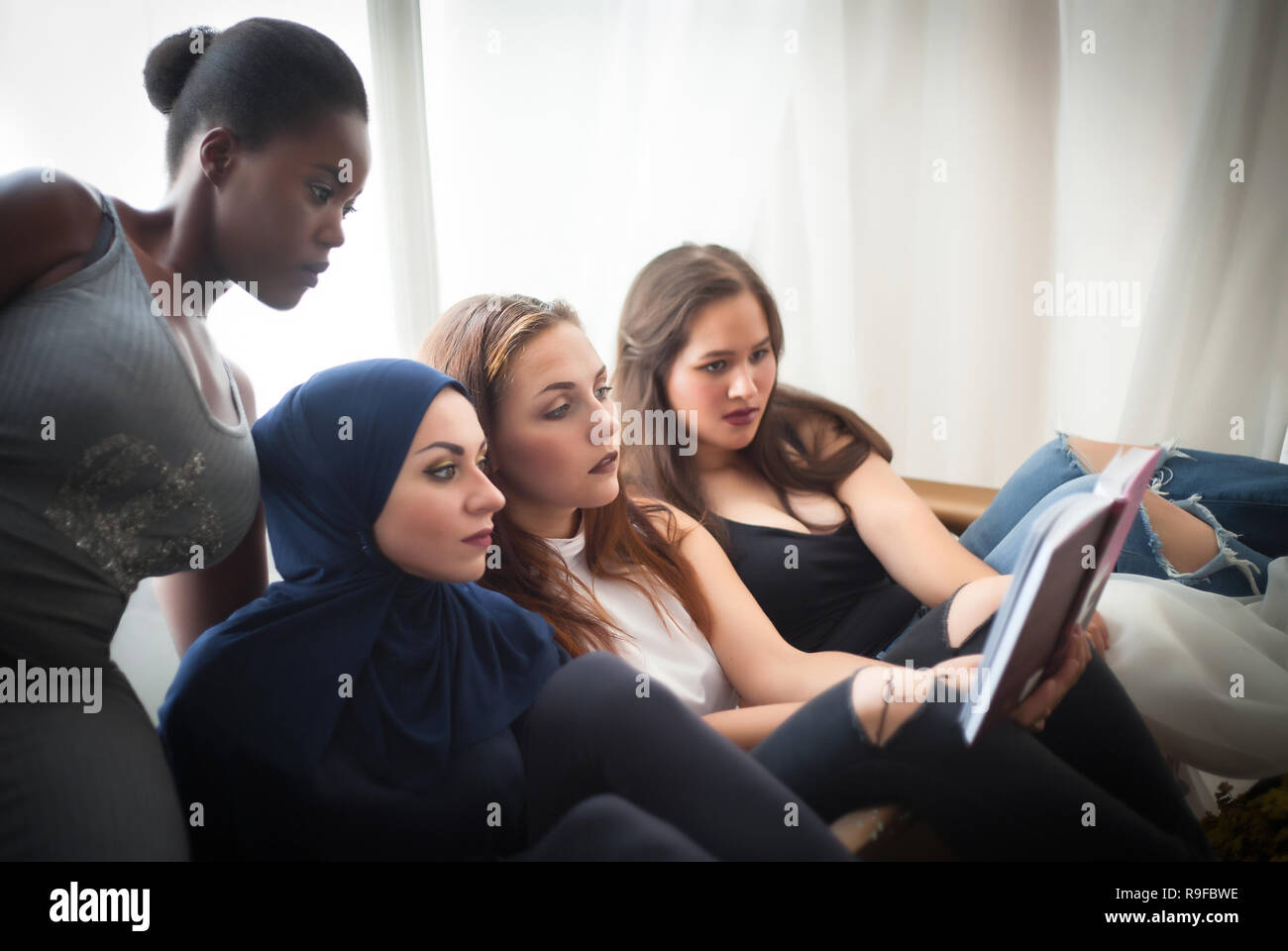 Portrait von vier Frauen verschiedener Nationalitäten ein Buch lesen im Studio. Stockfoto