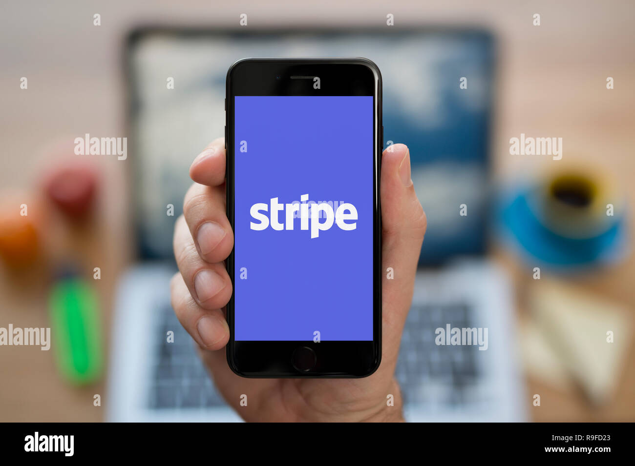 Ein Mann schaut auf seinem iPhone die zeigt die Stripe Logo (nur redaktionelle Nutzung). Stockfoto