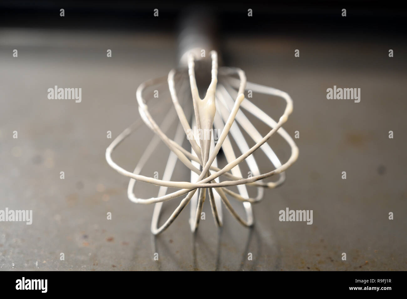Metalldraht Schneebesen mit Teig Reste auf einem grauen Backblech, Nahaufnahme, Ansicht mit Kopie Raum, ausgewählte konzentrieren und sehr enge Tiefenschärfe Stockfoto