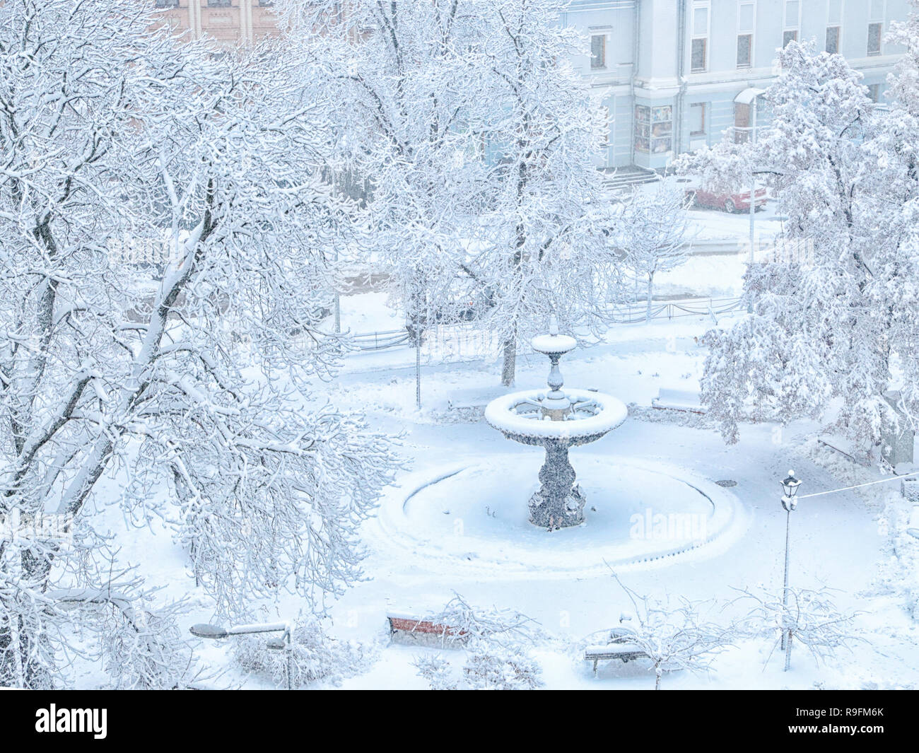 Brunnen auf Ivan Franko Square in Kiew, Ukraine im Winter mit Schnee bedeckt. Zweige gebeugt unter der Last des Schnees. Stockfoto