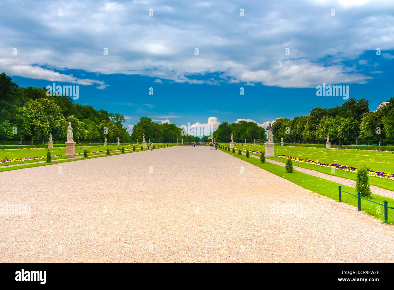 Schöne Aussicht auf den Französischen Garten mit seiner breiten Schotterweg in der Mitte des Großen Parterre von Schloss Nymphenburg. Das Barockschloss mit... Stockfoto