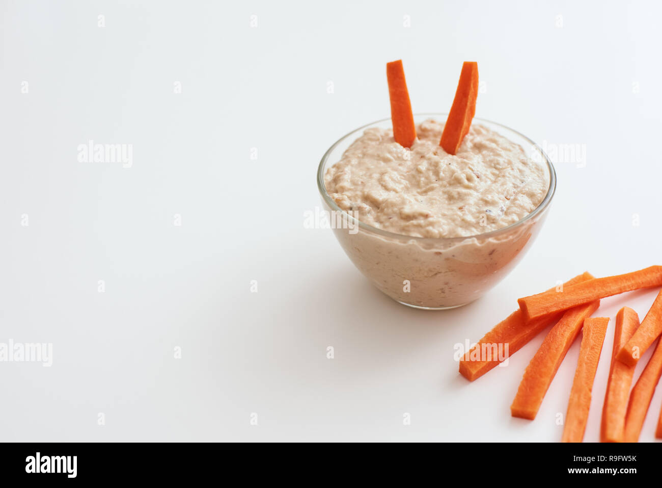 Schnellen Snack. Hummus mit Karotten Sticks. Foto von Humus mit Brote essen Balance auf weißem Hintergrund abgeschnitten. Stockfoto