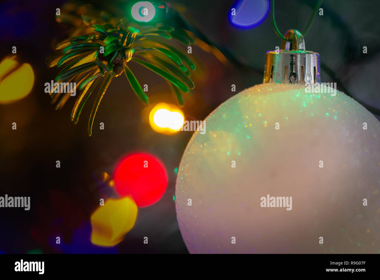 Nahaufnahme von einem weißen, Frosty christbaumkugel vor bunte Lichter am Weihnachtsbaum Stockfoto