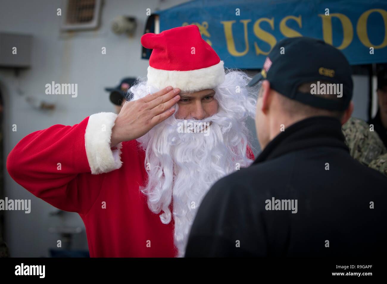 Rota, Spanien. 22 Dez, 2018. U.S. Navy sailor 1. Klasse Robert Camphouse,  verkleidet als Weihnachtsmann, begrüßt vor dem Aussteigen der  Arleigh-Burke-Klasse geführte Anti-raketen-Zerstörer USS Donald Cook als  das Schiff kommt an der