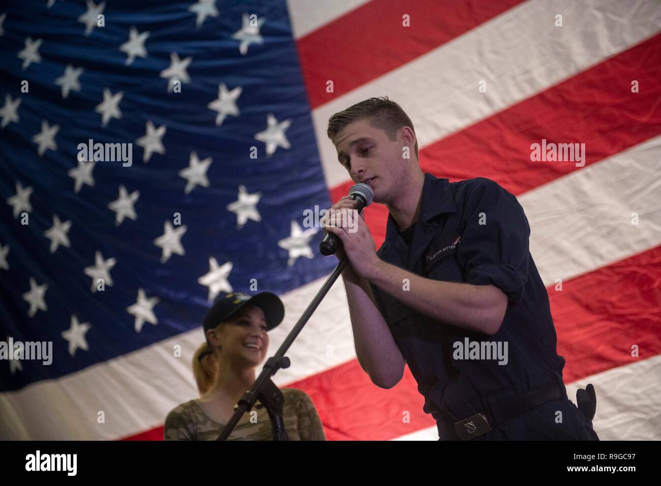 USS Stennis Air Craft Carrier, Oman. 23 Dez, 2018. Sailor Clayton Bitter versucht, seine Hand an einen Song als Country Music Star Kellie Pickler, schaut an während des Generalstabschefs USO Christmas Show für bereitgestellte Service Mitglieder an Bord der Flugzeugträger USS John C Stennis Dezember 23, 2018 im Persischen Golf. Unterhaltungskünstler in diesem Jahr gehören Schauspieler Milo Ventimiglia, Wilmer Valderrama, DJ J Dayz, stärkste Mann auf Erden Matt Fraser, 3-mal Olympiasieger Shaun White, Country Music Singer Kellie Pickler und Komiker Jessiemae Peluso. Credit: Planetpix/Alamy leben Nachrichten Stockfoto