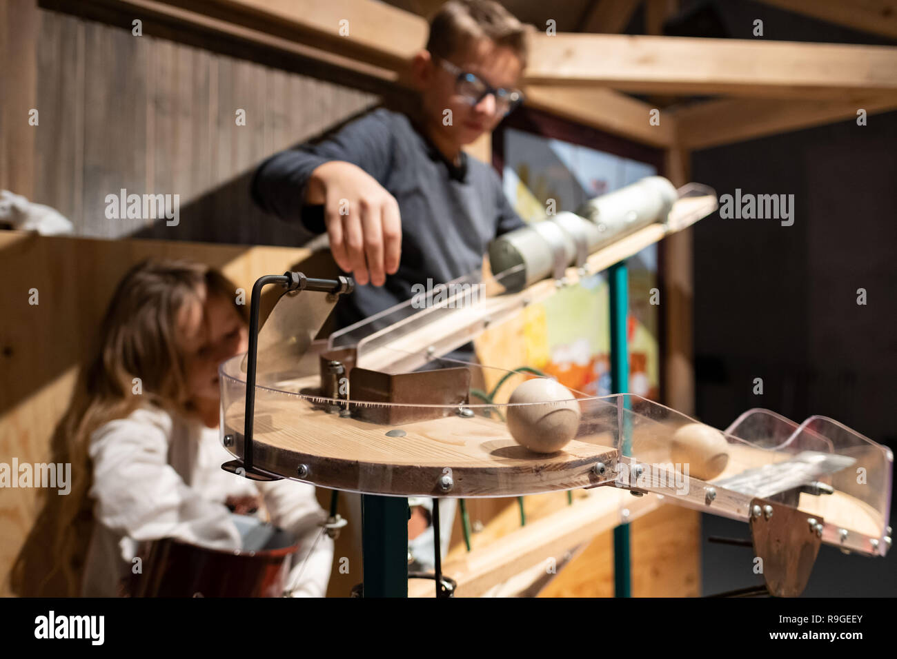 Wolfsburg, Deutschland. 23 Dez, 2018. Die besucher Noel (r) und Lia spielen Sie mit einem Holz- Maschine in der Sonderausstellung 'Tüftelmäuse' im Science Museum Phaeno. Mit dem 'Tüftelmäusen', die Ausstellung die Besucher eintauchen in eine Welt voller Fantasie, in der ihre erfinderischen Geist erwacht ist. In einem "Dachboden", sie erwarten zahlreiche interaktive Stationen, wo Sie ihren Einfallsreichtum beweisen können und ihre volle körperliche Engagement zeigen. Zusammen stellen sie die Maschinen in Bewegung mit Rädern, Gürtel und Zahnräder. Credit: Peter Steffen/dpa/Alamy leben Nachrichten Stockfoto