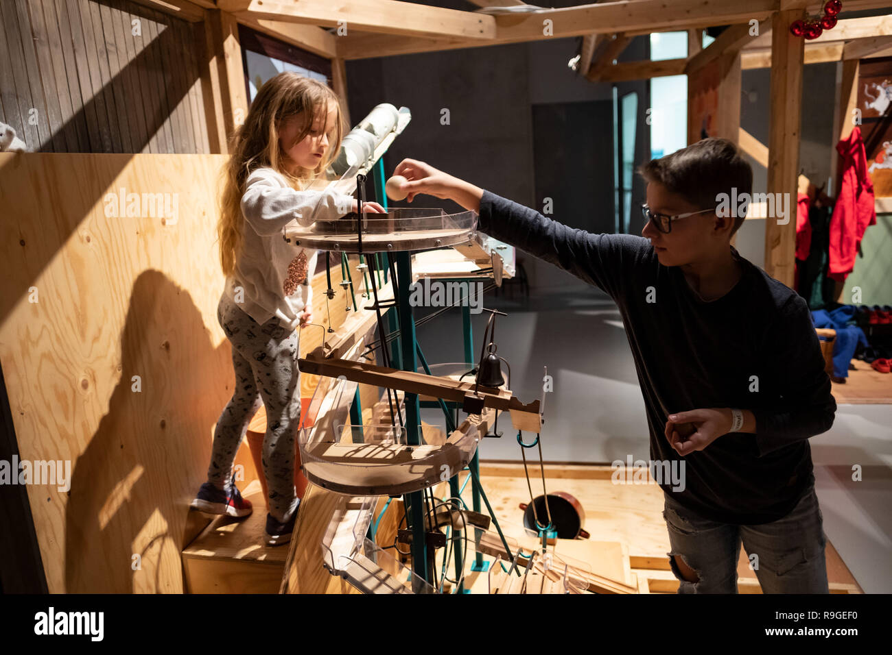 Wolfsburg, Deutschland. 23 Dez, 2018. Die besucher Noel (r) und Lia spielen Sie mit einem Holz- Maschine in der Sonderausstellung 'Tüftelmäuse' im Science Museum Phaeno. Mit dem 'Tüftelmäusen', die Ausstellung die Besucher eintauchen in eine Welt voller Fantasie, in der ihre erfinderischen Geist erwacht ist. In einem "Dachboden", sie erwarten zahlreiche interaktive Stationen, wo Sie ihren Einfallsreichtum beweisen können und ihre volle körperliche Engagement zeigen. Zusammen stellen sie die Maschinen in Bewegung mit Rädern, Gürtel und Zahnräder. Credit: Peter Steffen/dpa/Alamy leben Nachrichten Stockfoto