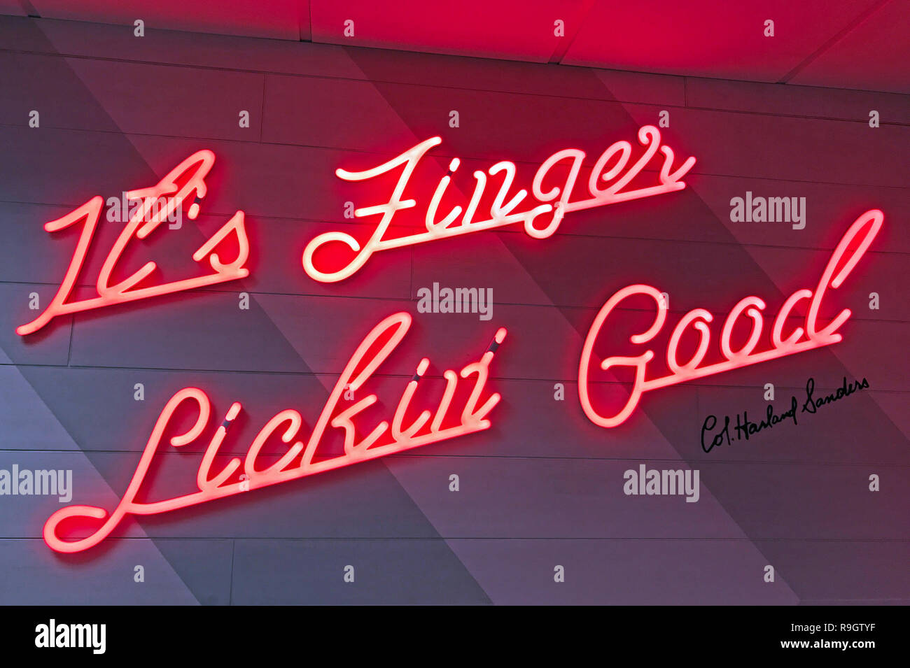 Seine Finger lecken Gut, Rot Neon KFC-Logo, gebratenes Huhn an einer Wand Stockfoto