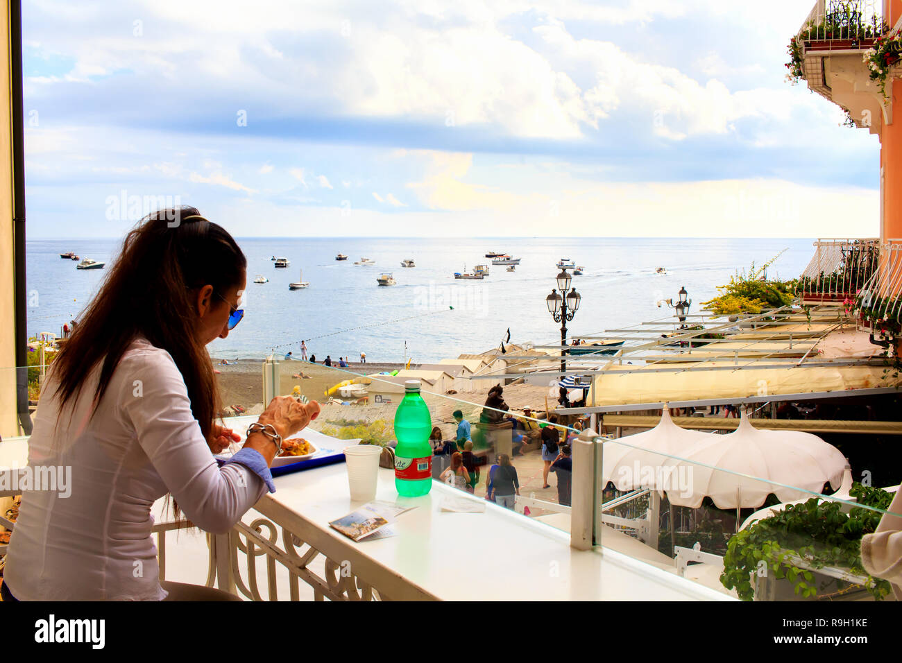 Frau, die ihr Essen auf der Terrasse im offenen Café in Positano, Amalfiküste, Italien, genießt Stockfoto
