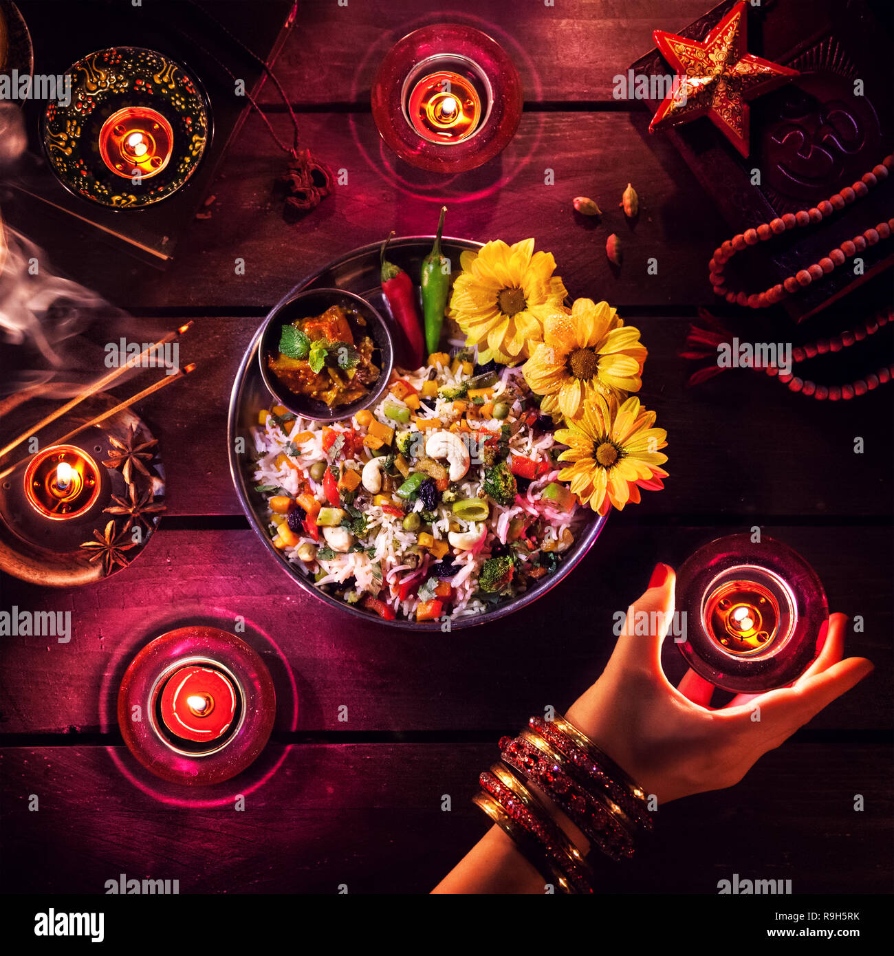 Vegetarische biryani, Kerzen, Weihrauch und religiöse Symbole in Diwali Feier auf dem Tisch Stockfoto