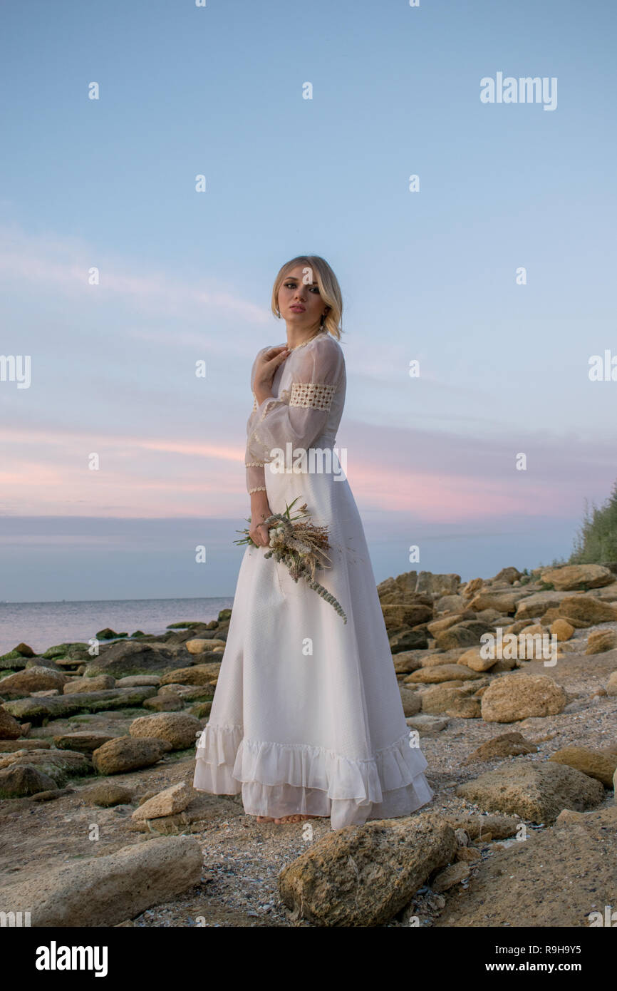 Elegante junge Frau in weißem Kleid auf Meer Hintergrund Stockfoto