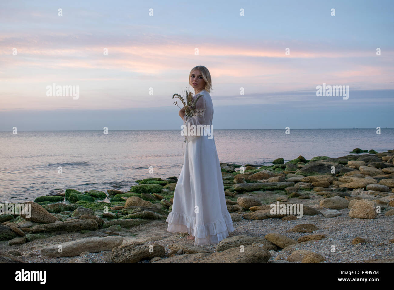 Elegante junge Frau in weißem Kleid auf Meer Hintergrund Stockfoto