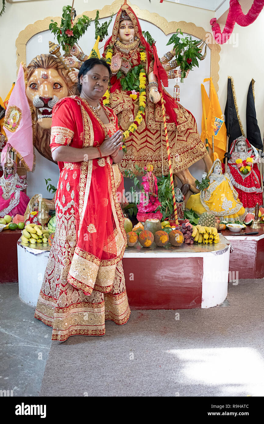 Portrait einer weiblichen Hindu Priester vor einer Statue der Göttin Durga. An einem Tempel in Jamaica, Queens, New York City. Stockfoto