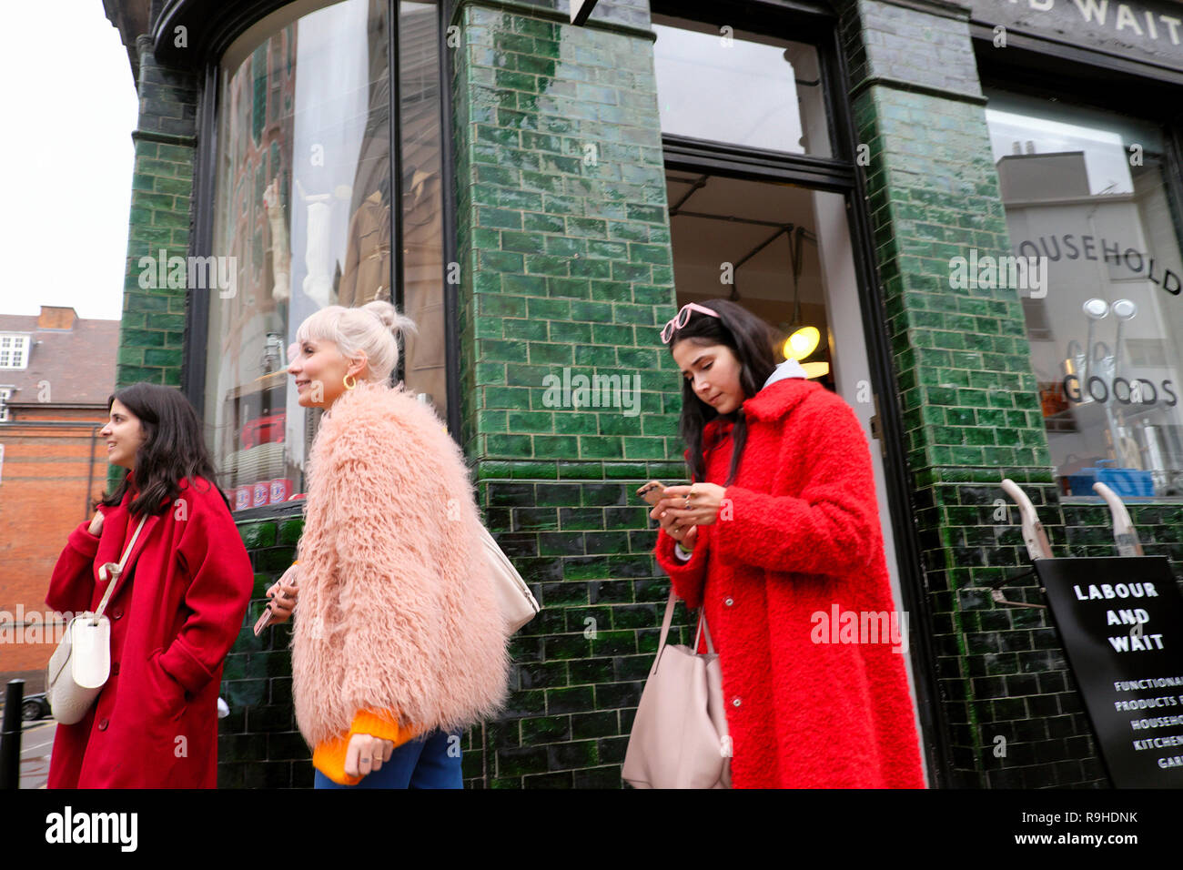 Trendige modische junge Frauen Shopper vor dem Labor und warten Shop im Winter in Redchurch Street Shoreditch East End London E2 UK KATHY DEWITT Stockfoto
